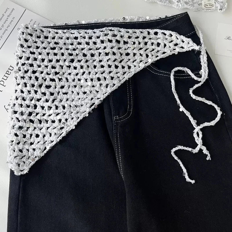 Foulard triangolare bianco con rete traforata e lacci da annodare, appoggiato su un paio di jeans neri