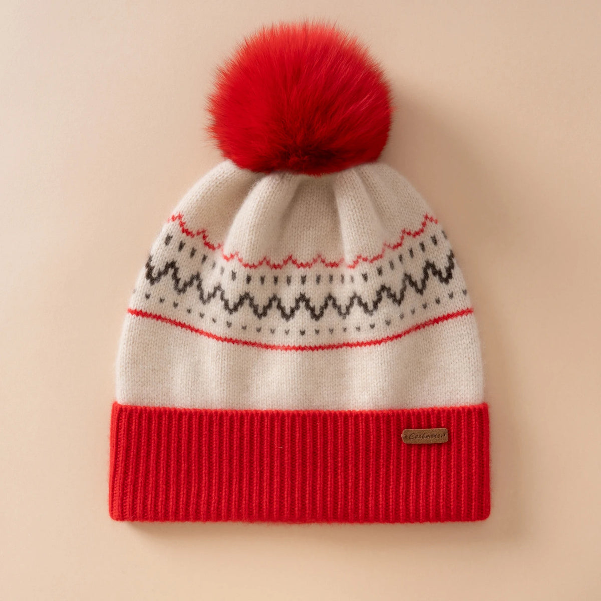 Berretto color crema con motivo nordico, risvolto rosso a coste e grande pompon dello stesso rosso
