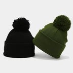Berretti con pompon nero e verde oliva, con risvolto ampio, fotografati insieme su sfondo bianco