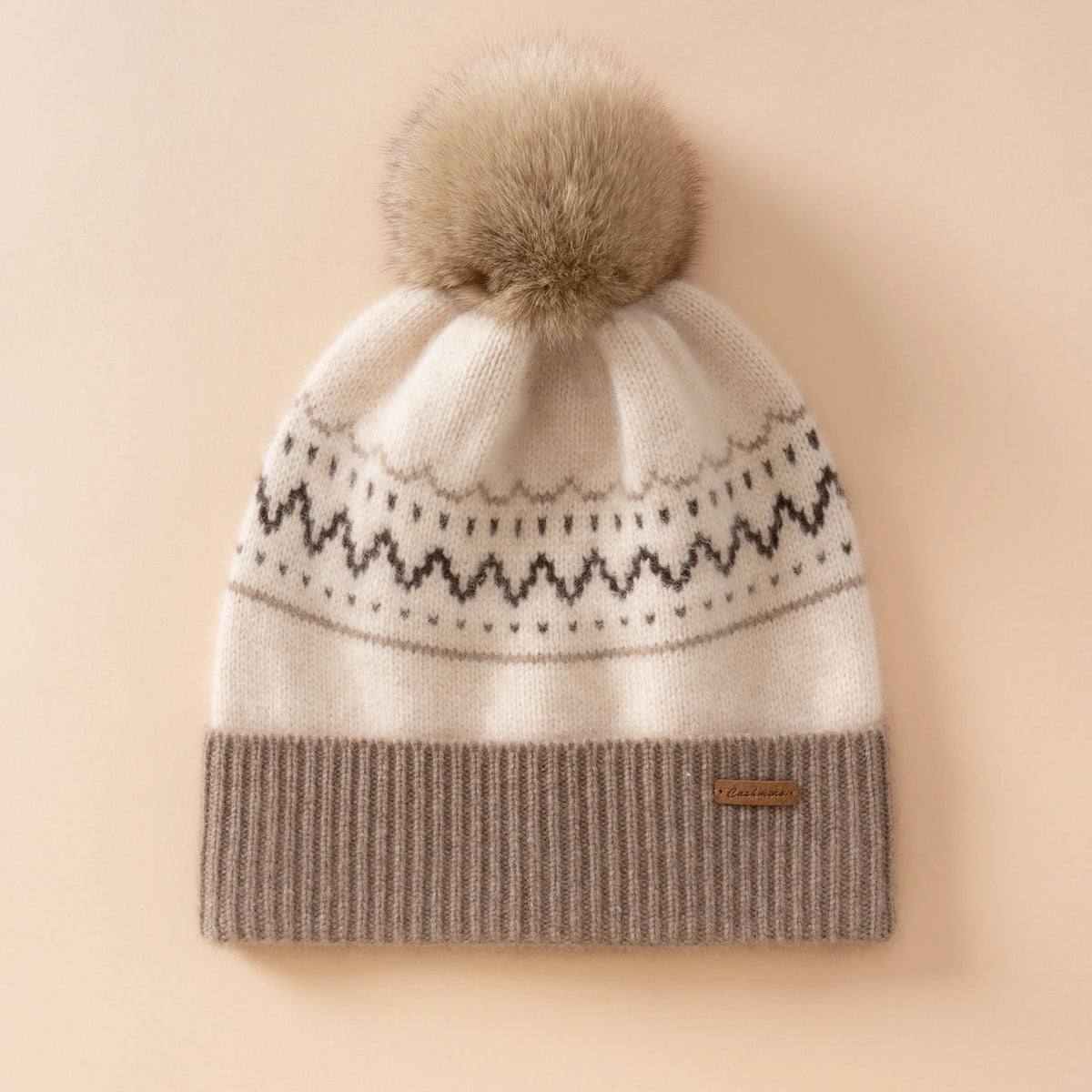 Berretto color crema con motivo nordico, risvolto a coste color tortora e pompon nei toni beige e marrone
