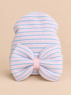 Cappellino da neonata in cotone a righe rosa e blu con grande fiocco, fotografato nella vista frontale