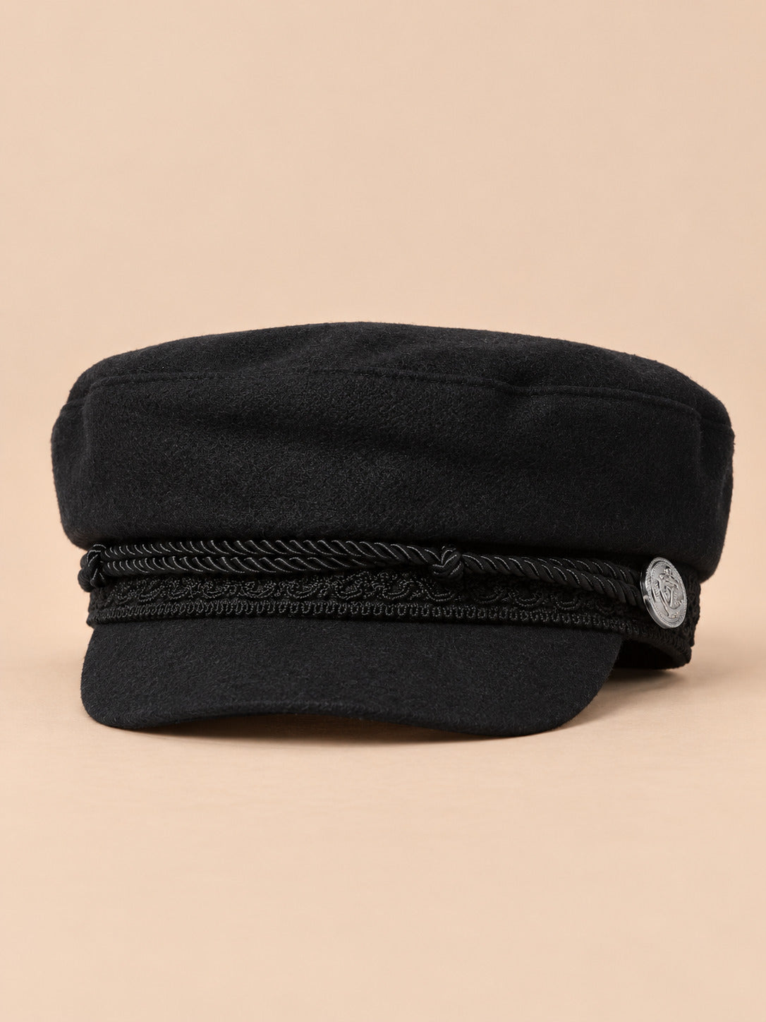 Cappello da marinaio nero a otto spicchi con visiera, stile capitano, su sfondo color sabbia e pesca
