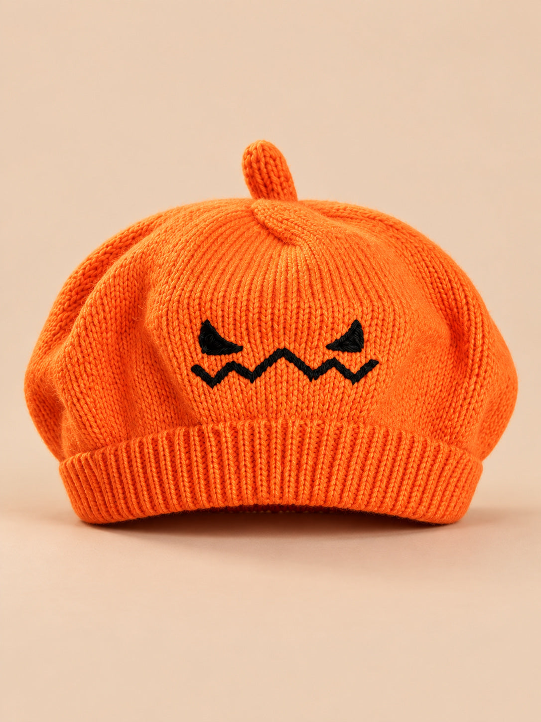 Basco arancione da bambino in maglia con viso di zucca ricamato per Halloween, fotografato di fronte