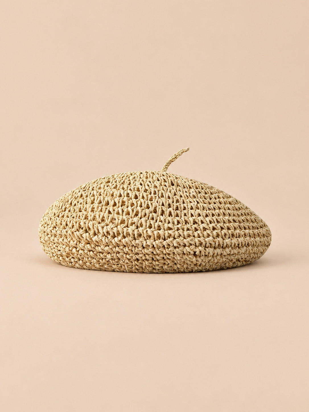 Basco estivo piatto beige effetto paglia, stile bohémien, visto di fronte su sfondo sabbia e pesca