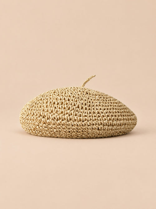 Basco estivo piatto beige effetto paglia, stile bohémien, visto di fronte su sfondo sabbia e pesca