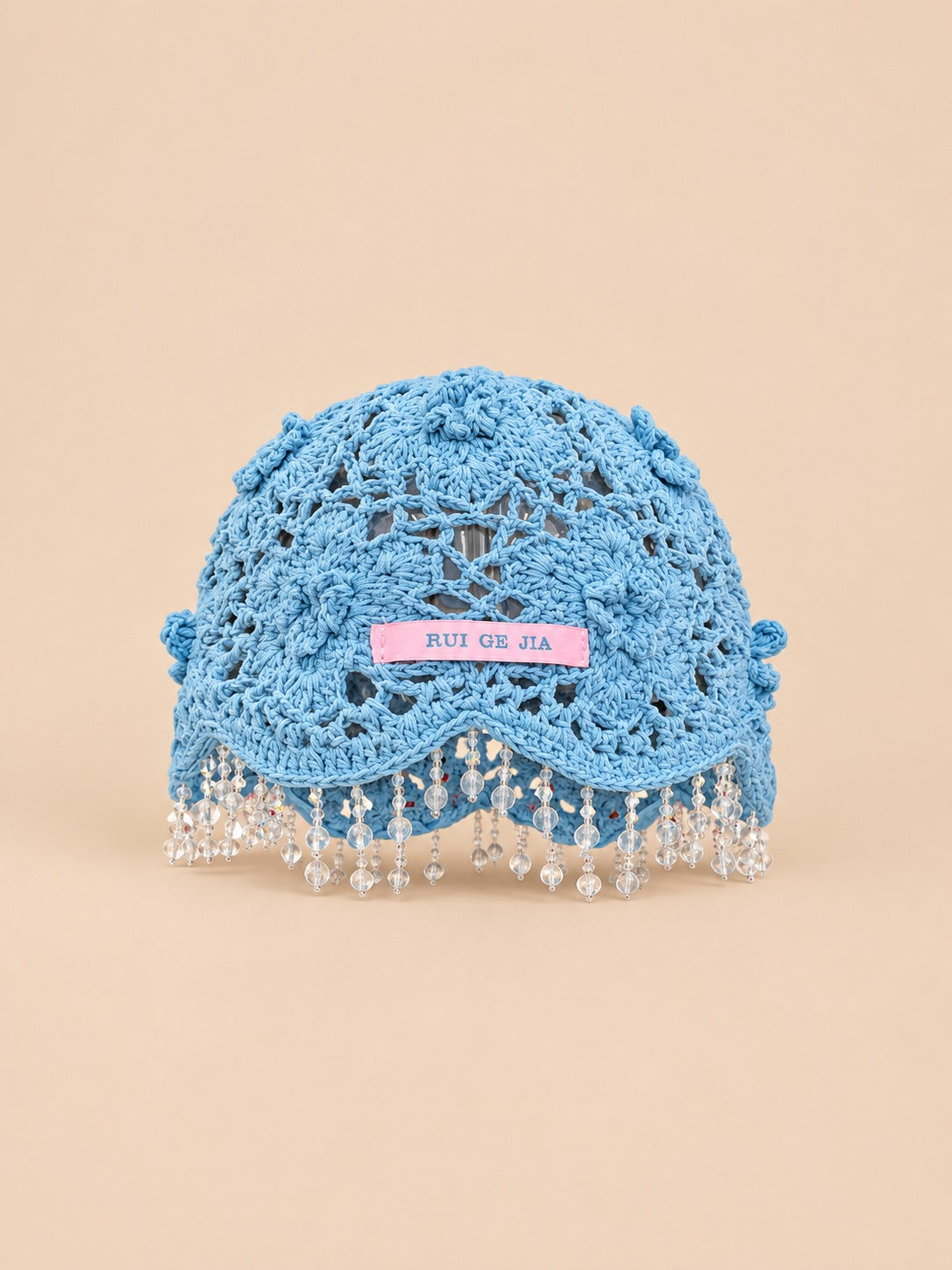 Cappello bohémien da donna a rete azzurro cielo, con perline, pompon e fiori all’uncinetto, vista frontale