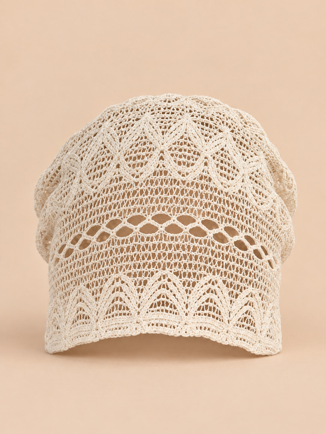 Cappello a calotta beige a rete arricciata, in stile coreano, vista frontale su sfondo sabbia e pesca
