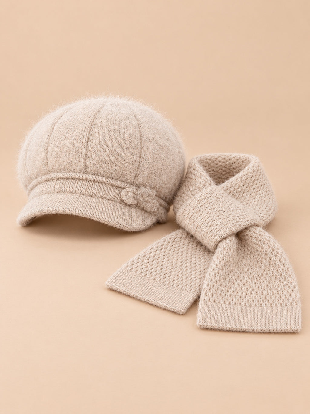 Set da donna beige composto da cappello soffice e sciarpa lavorata a maglia, fotografato di fronte
