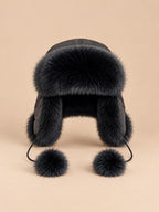 Colbacco nero da donna in pelliccia di volpe con pompon decorativi e paraorecchie, visto di fronte