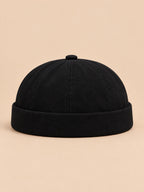 Berretto docker nero in denim con risvolto e cinturino regolabile, stile workwear, fotografato di fronte