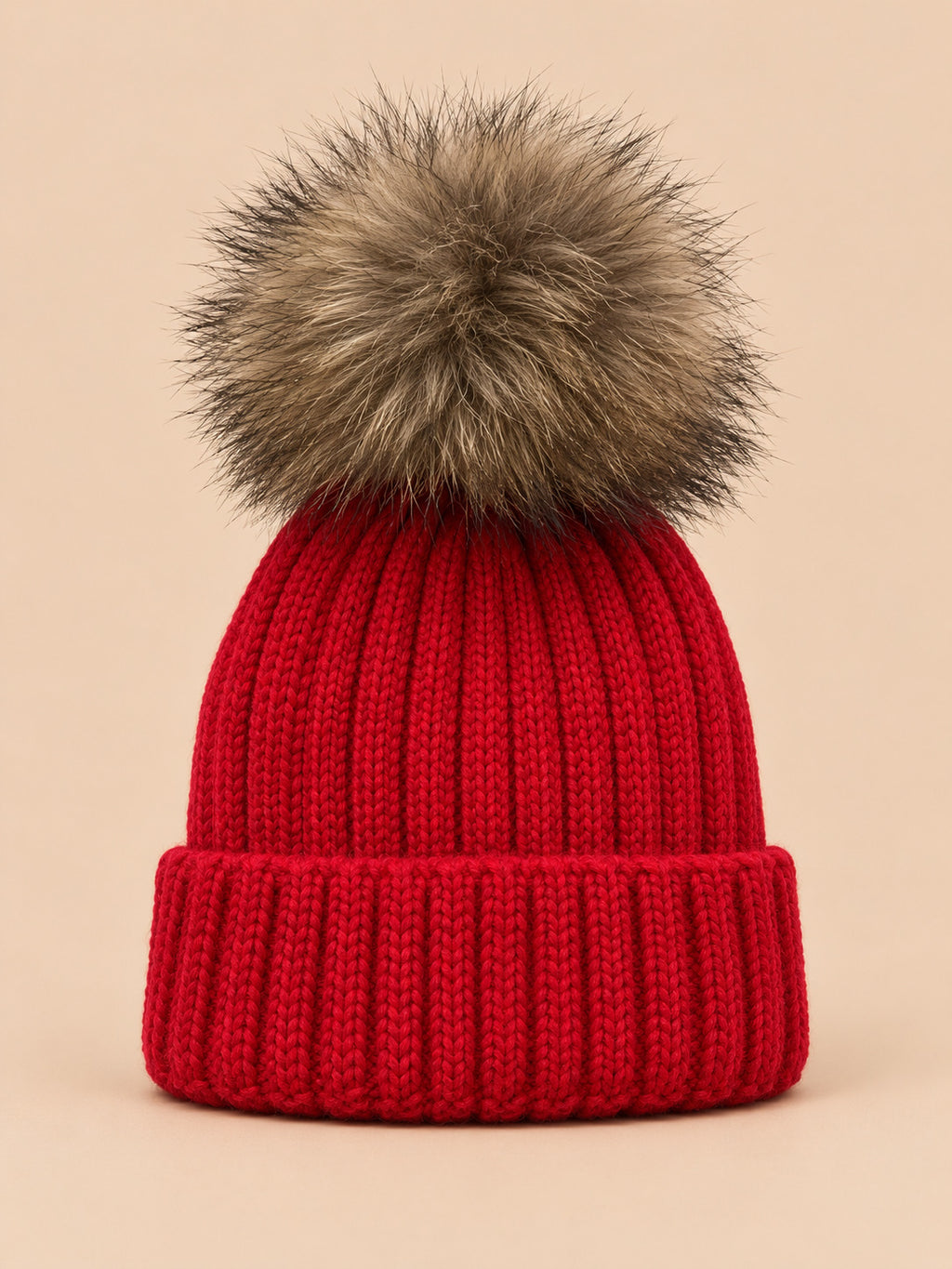 Berretto rosso da bambino con pompon, parte del set berretto e sciarpa, su sfondo color sabbia e pesca
