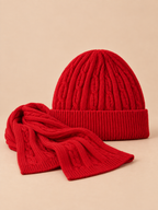 Set berretto e sciarpa rosso in lana jacquard spessa, visto di fronte su sfondo color sabbia e pesca