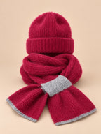 Set berretto e sciarpa da donna bordeaux in maglia effetto peluche, su sfondo color sabbia e pesca
