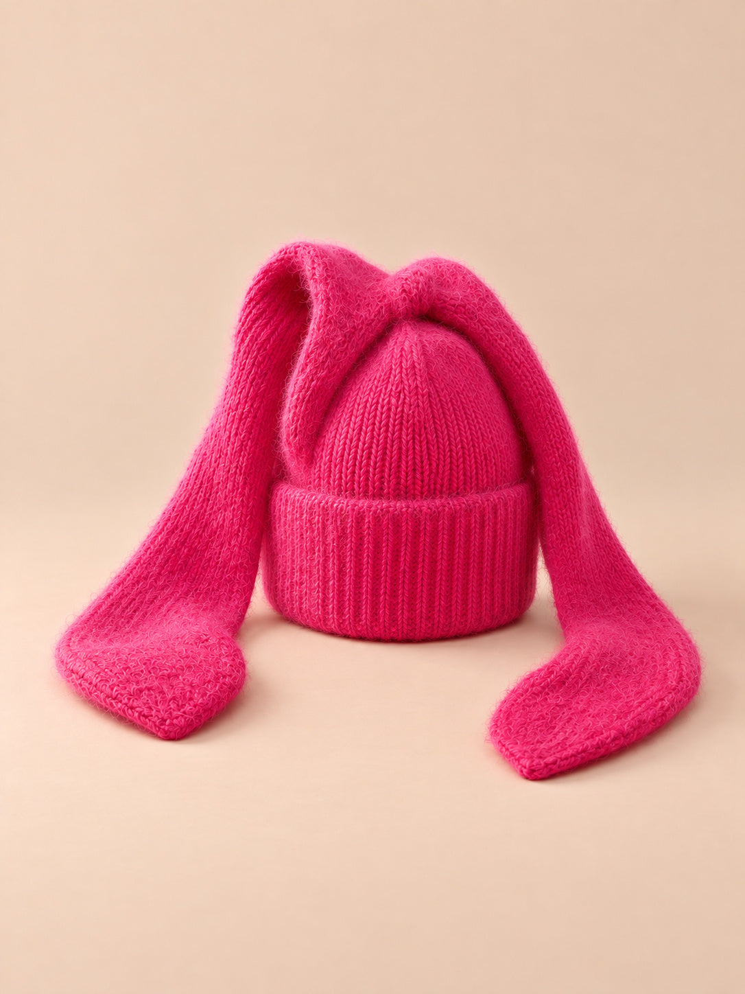 Berretto da donna all’uncinetto e a maglia con orecchie da coniglio, colori rosso e fucsia, vista di tre quarti