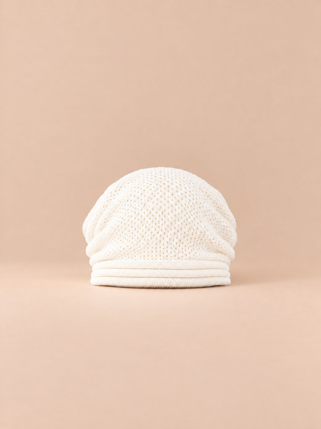 Berretto oversize bianco in maglia calda e antivento, visto di fronte su sfondo sabbia e pesca