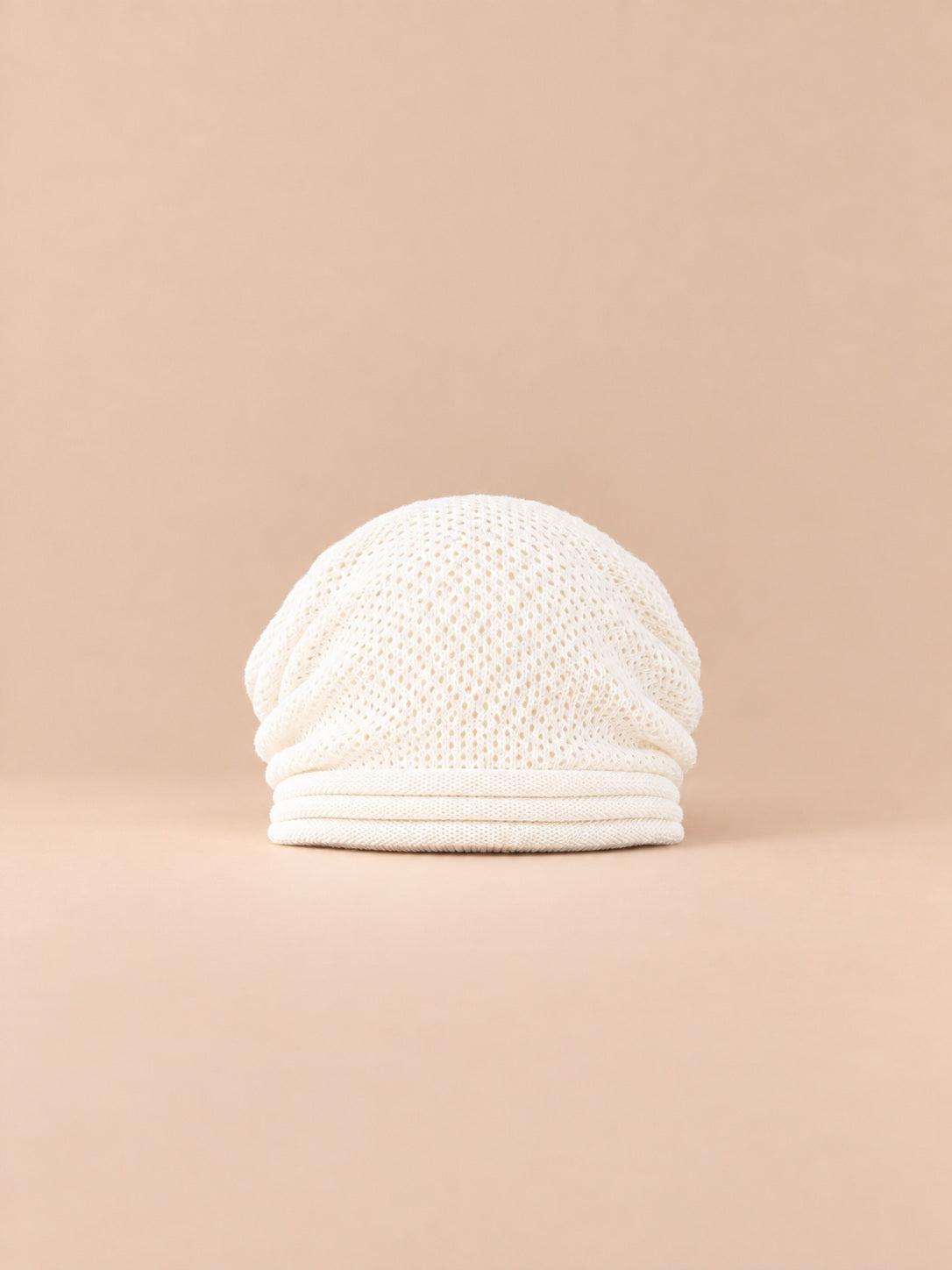 Berretto oversize bianco in maglia calda e antivento, visto di fronte su sfondo sabbia e pesca