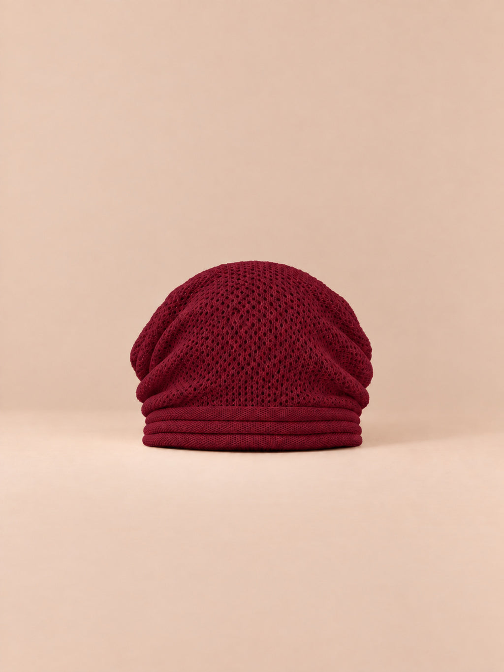 Berretto oversize in maglia caldo e antivento, colore rosso, vista frontale, su sfondo color sabbia e pesca
