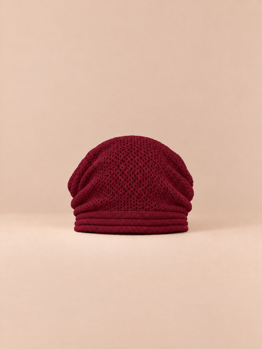 Berretto oversize in maglia caldo e antivento, colore rosso, vista frontale, su sfondo color sabbia e pesca