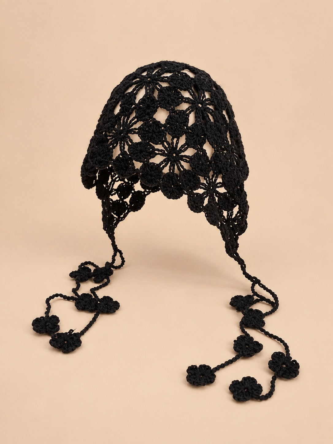 Cappello da pescatore nero con fiori traforati e forma morbida che avvolge la testa, visto di fronte