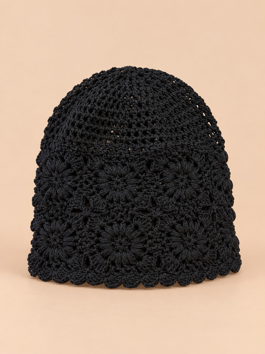 Turbante nero da donna a rete a coste, modello proposto in sei colori, su sfondo color sabbia e pesca