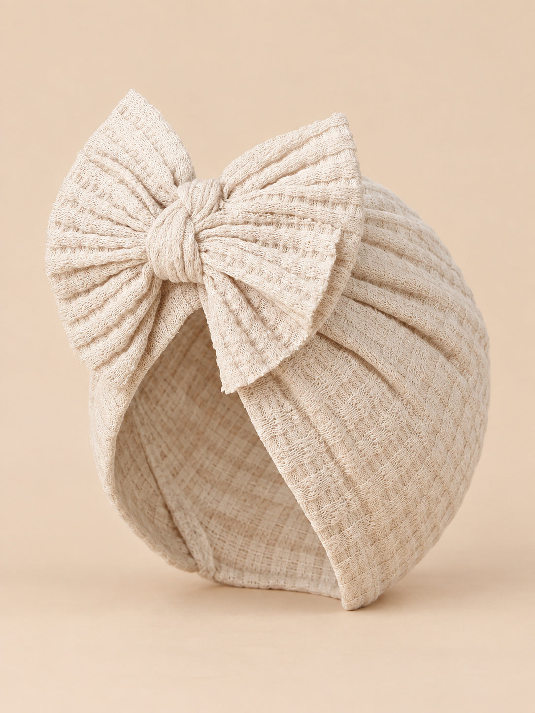Turbante da neonata con fiocco in cotone lavorato a maglia, colore beige, vista di tre quarti