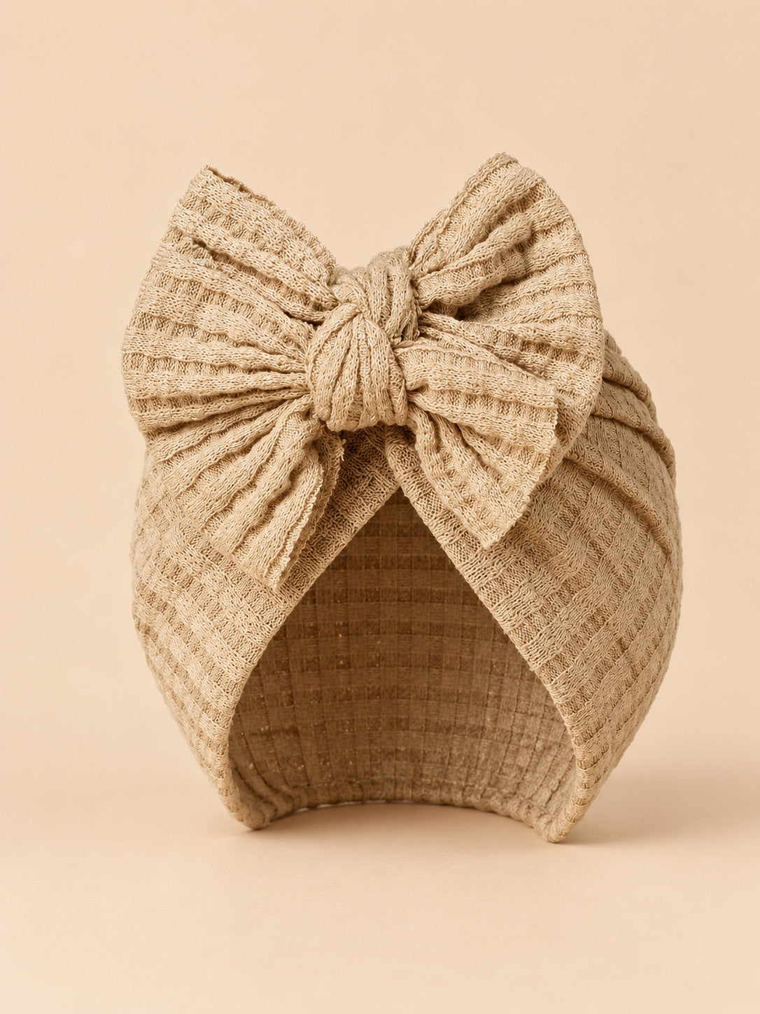 Turbante da neonata con fiocco in cotone lavorato a maglia, colori beige e sabbia, vista frontale